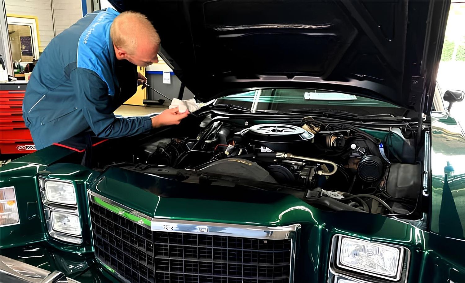 Ein Mann prüft den Motorraum eines grünen Oldtimers
